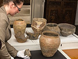 Rashida Hussein Oglü mit spätbronze- bis früheisenzeitlichen Urnen und Beigefäßen aus dem Stadtmuseum Lippstadt. Foto: Peter Freitag/Stadtmuseum Lippstadt.